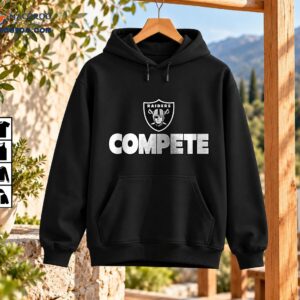 Compete Distressed Football Shield Graphic Shirt 3 Distressed black and white shield emblem with a helmeted figure, crossed swords, RAIDERS text, and bold COMPETE lettering